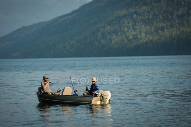 Due pescatori che bevono birra mentre pescano nel fiume in campagna — Foto stock