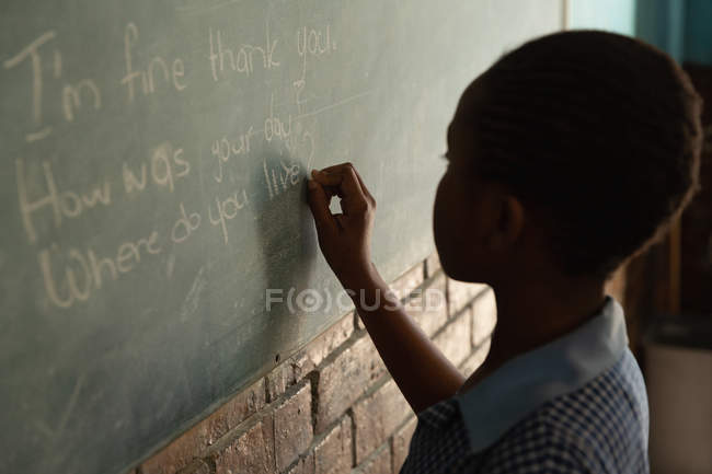 Studentessa che scrive sulla lavagna in classe a scuola — Foto stock