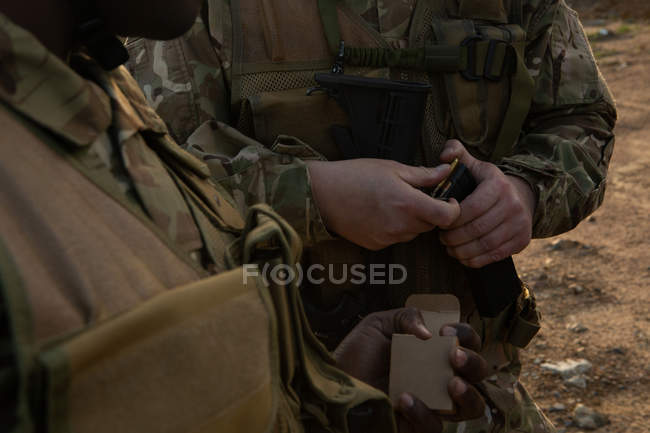 Mid section of military soldiers holding magazine during military training — Stock Photo