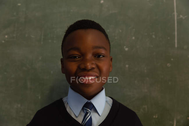 Schoolboy de pé perto de quadro-negro em sala de aula na escola — Fotografia de Stock