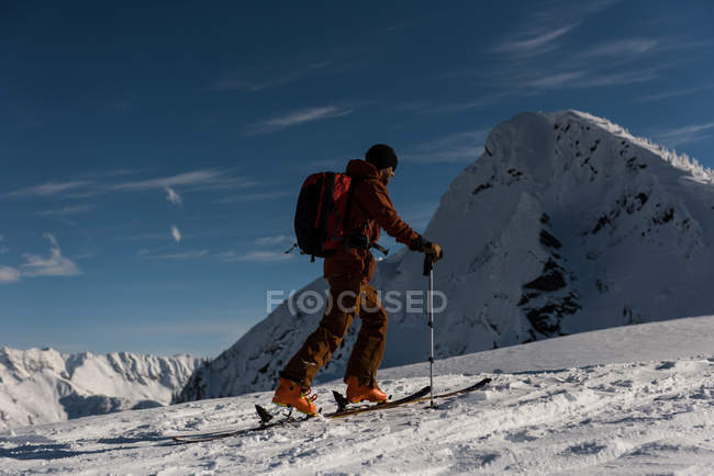 Esquiador masculino caminhando em uma montanha nevada durante o inverno — Fotografia de Stock