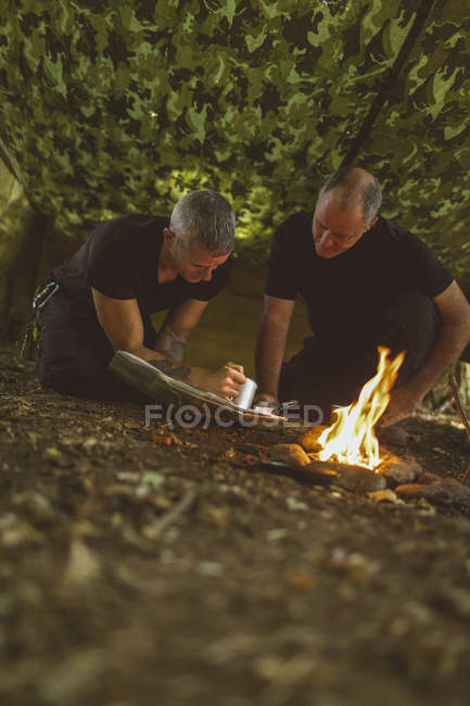 Двоє підходящих чоловіків дивляться на карту в таборі для завантаження — стокове фото