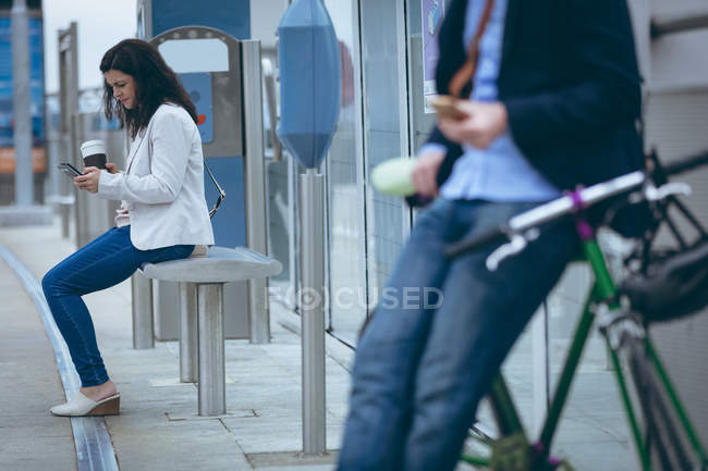 Молода бізнес-леді, використовуючи мобільний телефон на залізничній станції — стокове фото