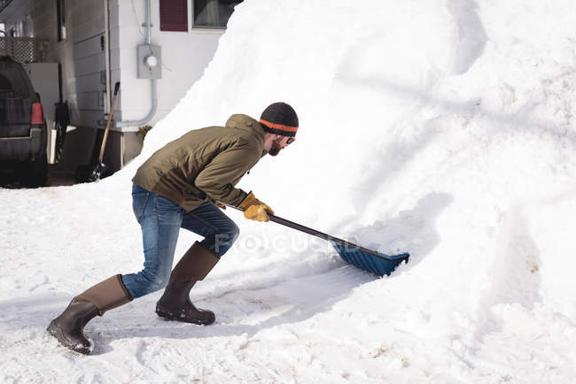 Hombre limpiando nieve con empujador de nieve durante el invierno - foto de stock