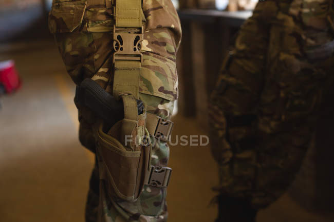 Sección media del soldado militar de pie con pistola durante el entrenamiento militar - foto de stock