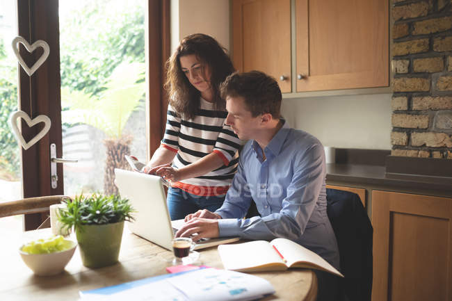 Молодая пара обсуждает за цифровой планшет на кухне дома — стоковое фото