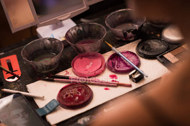Крупный план различных красок и коробки для макияжа хранится на столе — стоковое фото