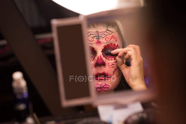 Woman placing artificial eye lashes on her eyes for halloween celebration — Stock Photo