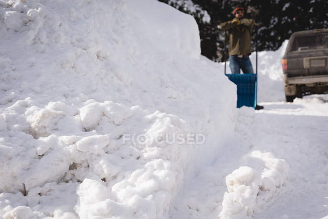 Man cleaning snow with snow pusher during winter — Stock Photo