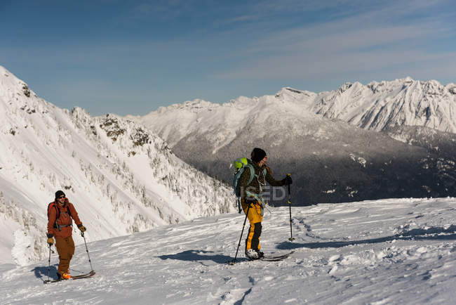 Лыжники, идущие по снежной горе зимой — стоковое фото