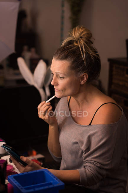 Woman applying makeup for halloween celebration — Stock Photo