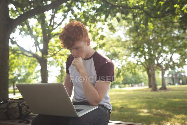 Estudiante atento de la universidad usando el ordenador portátil en el campus - foto de stock