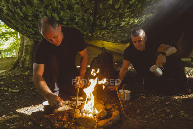 Fit men lighting fire at boot camp — Stock Photo