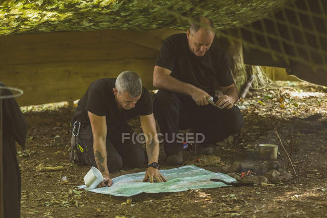 Zwei fitte Männer schauen im Bootslager auf Landkarte — Stockfoto