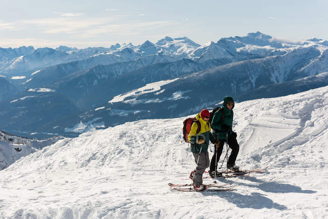 Esquiadores y esquiadoras caminando en una montaña nevada durante el invierno - foto de stock