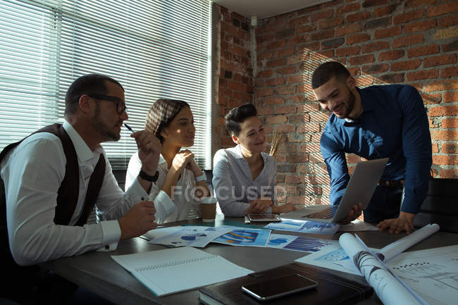 Руководители обсуждают за ноутбуком в конференц-зале в офисе — стоковое фото