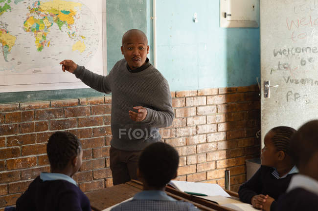 Male teacher teaching students in the classroom at school — Stock Photo