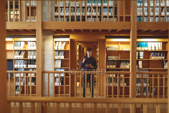 Studente universitario con tablet digitale guardando la fotocamera in biblioteca — Foto stock