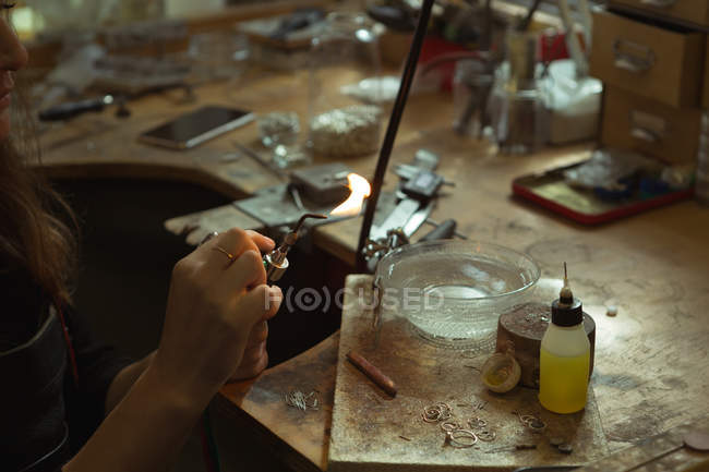 Schmuckdesignerin hält schwingende Fackel in Werkstatt — Stockfoto