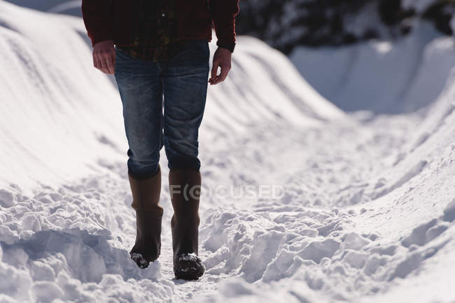 Low section of man walking on a snowy region during winter — Stock Photo