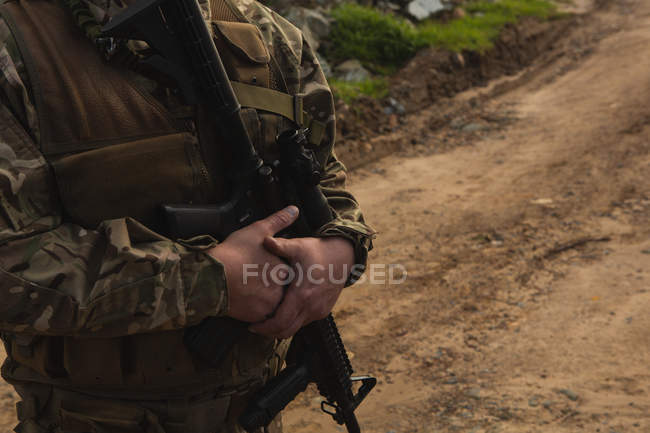 Mid section of military soldier standing with rifle during military training — Stock Photo