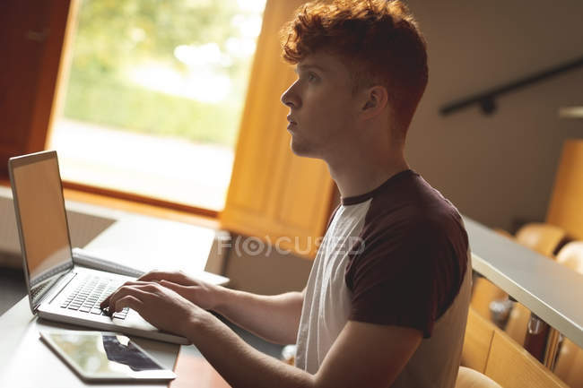 Вид сбоку на студента колледжа, использующего ноутбук в классе — стоковое фото