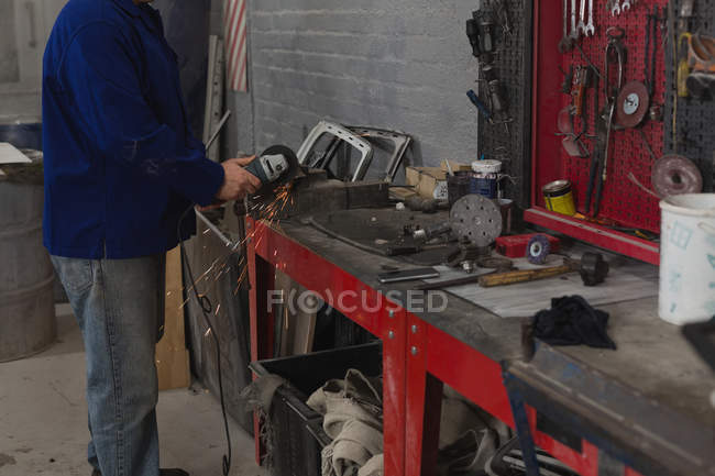 Baixa seção da máquina de moagem mecânica masculina na garagem — Fotografia de Stock