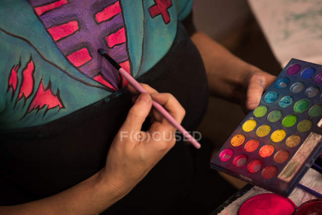 Woman painting her body for halloween celebration — Stock Photo