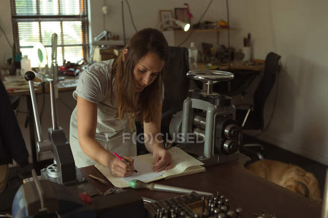 Жіночий ювелірний дизайнер писати в реєстрі в майстерні — стокове фото