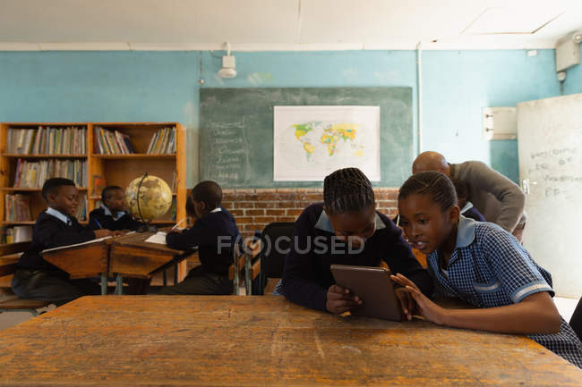 Crianças em idade escolar usando tablet digital em sala de aula na escola — Fotografia de Stock