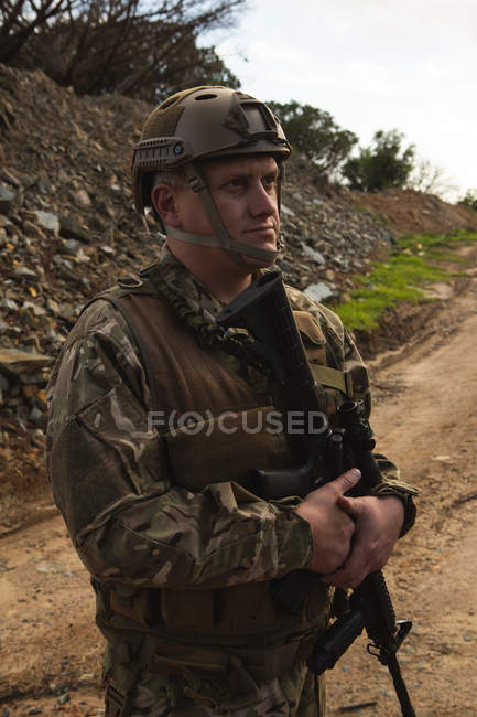 Військовослужбовець стоїть з гвинтівкою під час військової підготовки у військовому таборі — стокове фото