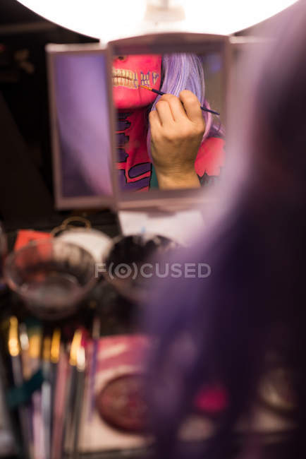 Mulher pintando seu rosto com escova para a celebração do dia das bruxas — Fotografia de Stock