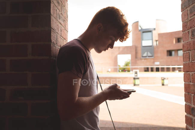 College student using mobile phone in corridor — Stock Photo