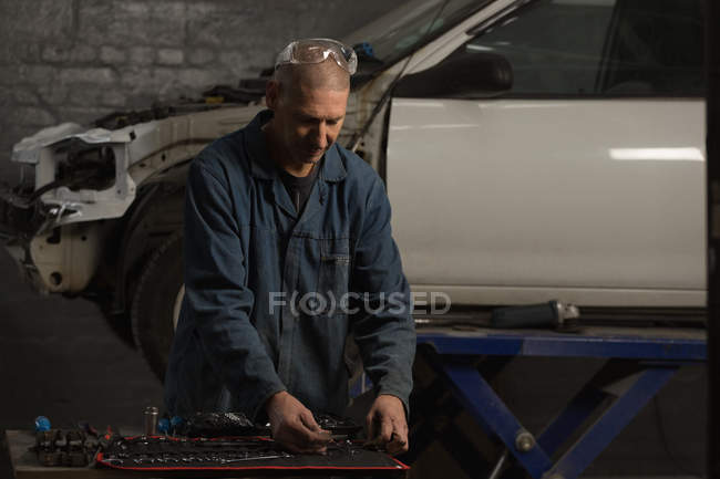 Mecánico masculino seleccionando herramientas en garaje - foto de stock