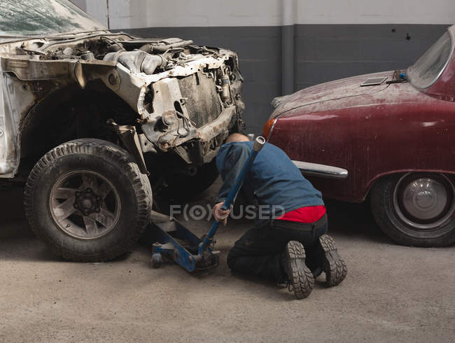 Mecânico masculino usando trole jack na garagem — Fotografia de Stock