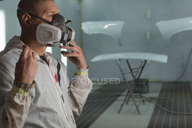Vue latérale du mécanicien portant un masque à gaz dans le garage — Photo de stock