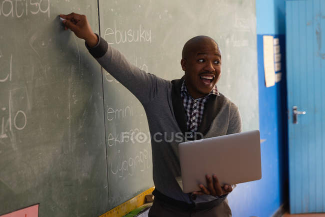 Profesor masculino explicando en pizarra en el aula - foto de stock