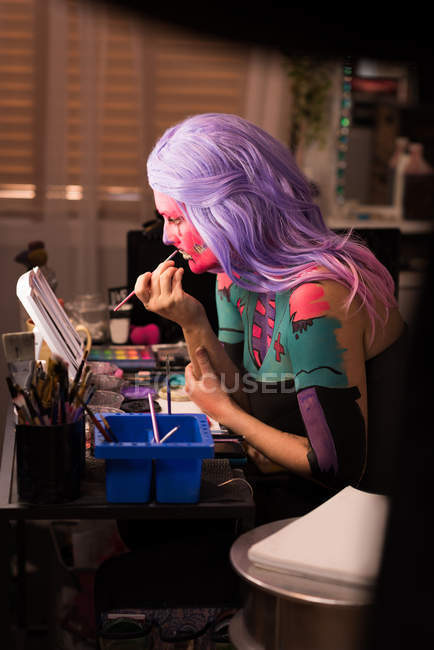Woman painting her face with brush for halloween celebration — Stock Photo