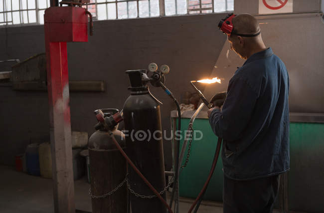 Чоловічий механічний перевірка зварювання факела в гаражі — стокове фото