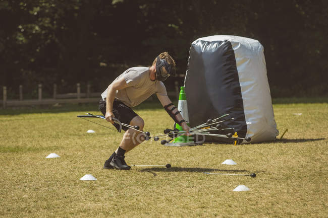 Homme ramassant flèche dans l'entraînement au camp d'entraînement — Photo de stock