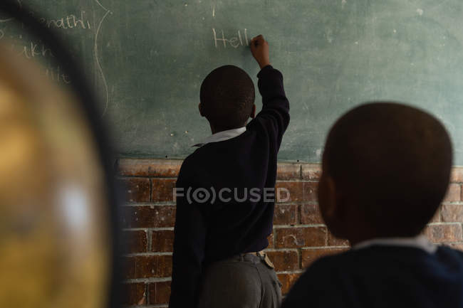 Schüler schreibt auf Kreide im Klassenzimmer der Schule — Stockfoto