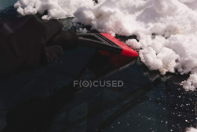 Nahaufnahme eines Mannes, der Schnee von der Windschutzscheibe des Autos reinigt — Stockfoto