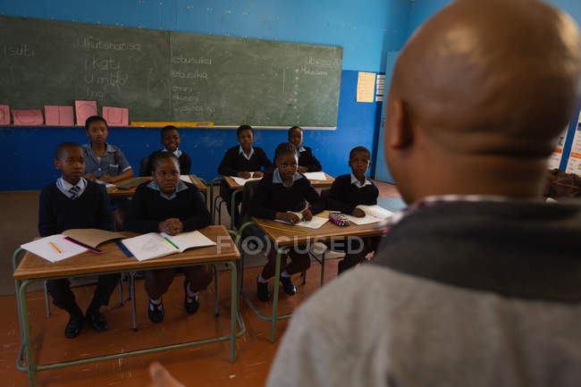 Profesor masculino enseñando a los estudiantes en el aula en la escuela - foto de stock