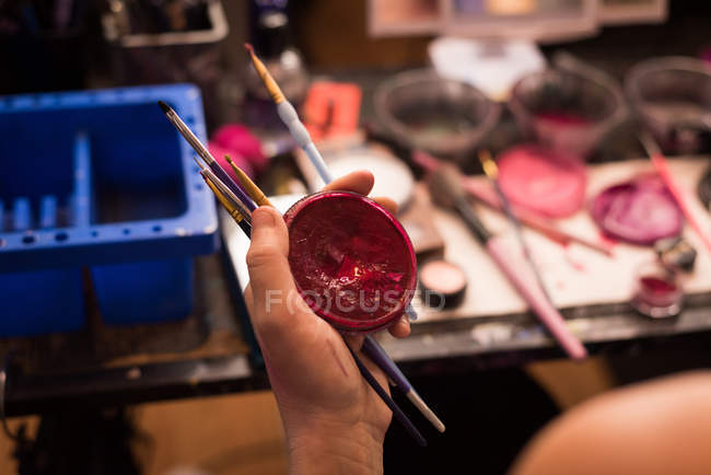 Close-up de mulher segurando recipiente de tinta vermelha e escovas — Fotografia de Stock