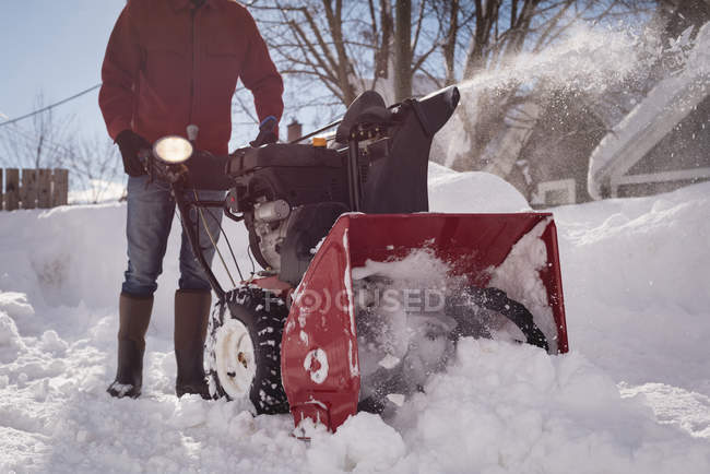 Homem usando máquina de ventilador de neve na região nevada durante o inverno — Fotografia de Stock