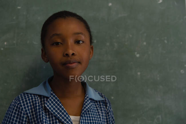 Schülerin steht neben Kreidetafel im Klassenzimmer der Schule — Stockfoto
