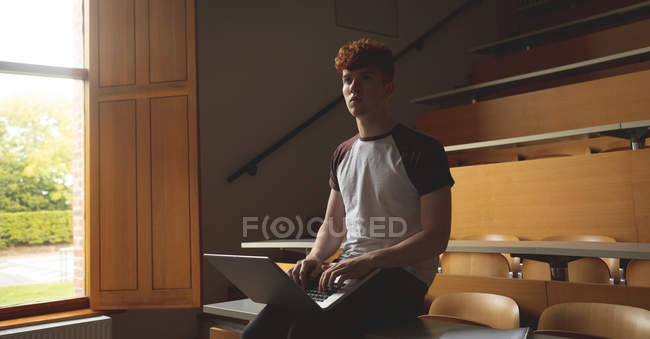 Jovem estudante universitário usando laptop em sala de aula — Fotografia de Stock