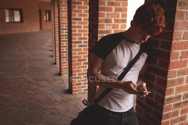 College student using mobile phone in corridor — Stock Photo