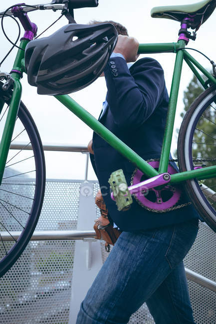 Бизнесмен поднимается по лестнице на велосипеде на открытом воздухе — стоковое фото