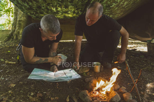Двоє підходящих чоловіків дивляться на карту в таборі для завантаження — стокове фото
